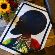 Chris Ofili Afromuses tea towel by soulPhoodie on table beside flowers, showcasing Black art design.