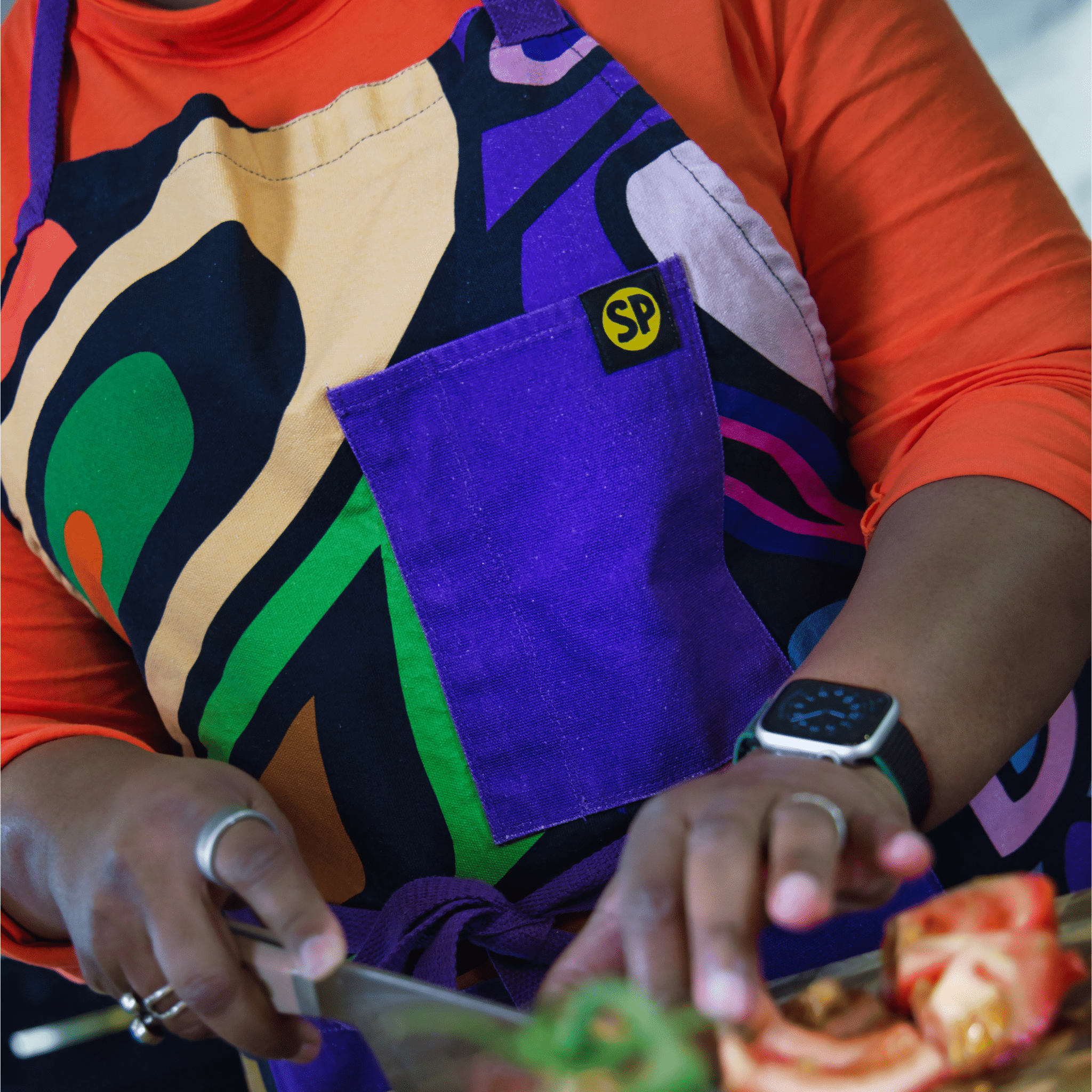 Picture of cook wearing the Aravella Apron with bold abstract pattern and purple pocket from Black-owned brand soulPhoodie