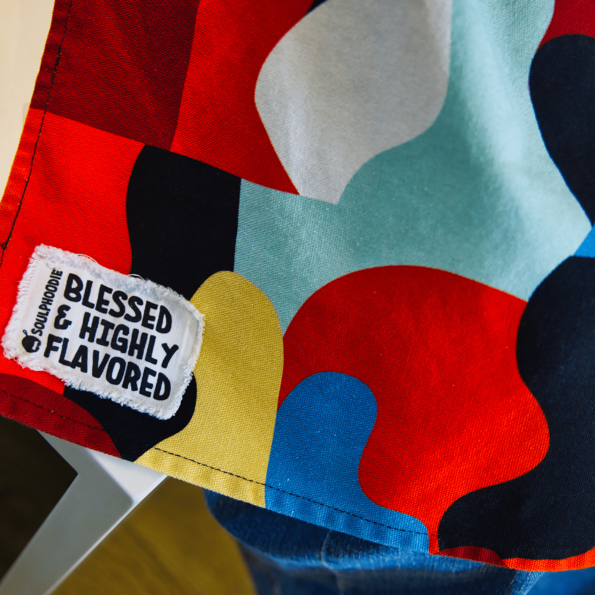 Close-up of Blessed and Highly Flavored tag on colorful Beryl Apron by Black-owned brand soulPhoodie