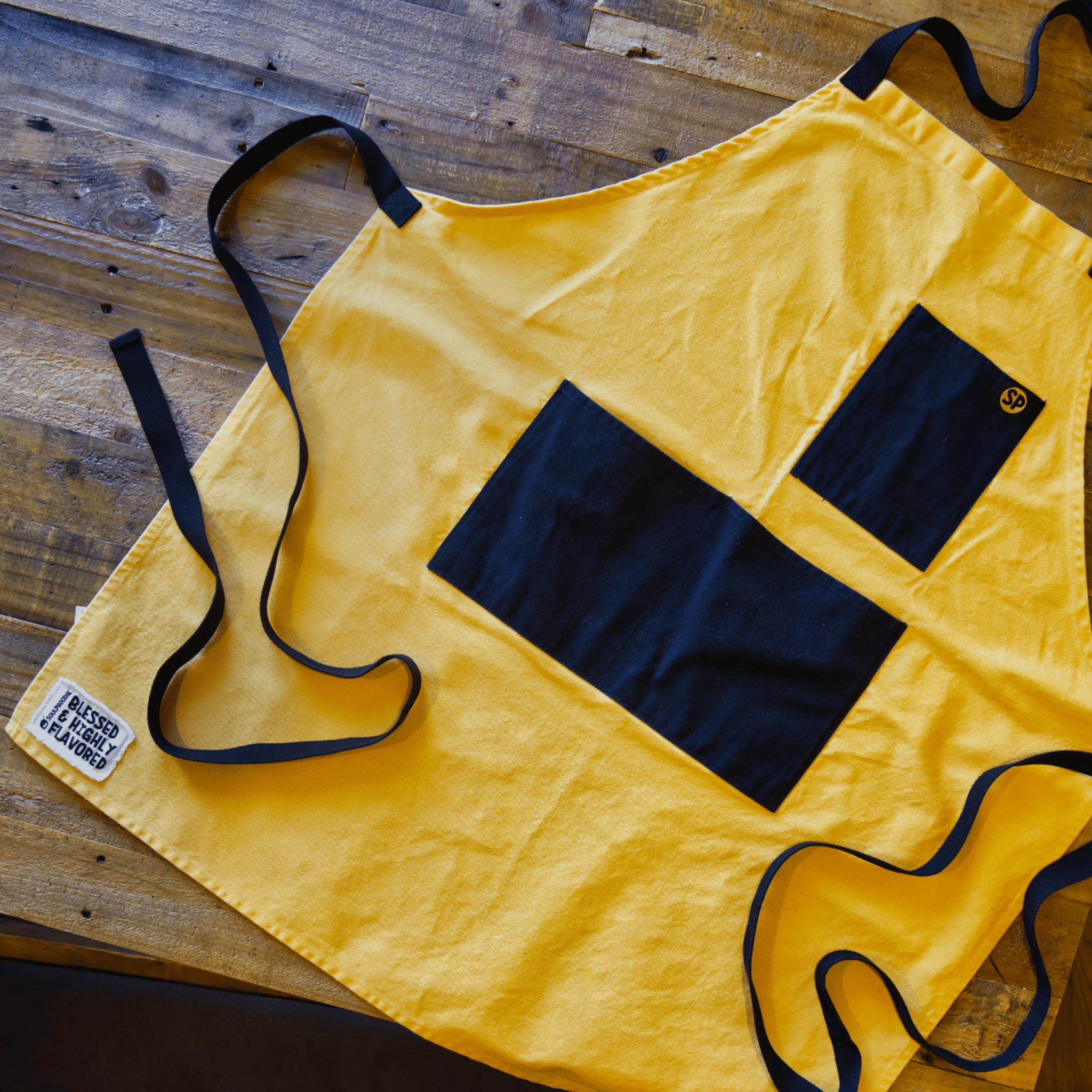 Cornbread Gold Apron from Black-owned brand soulPhoodie featuring bold gold canvas with black pockets and ties.
