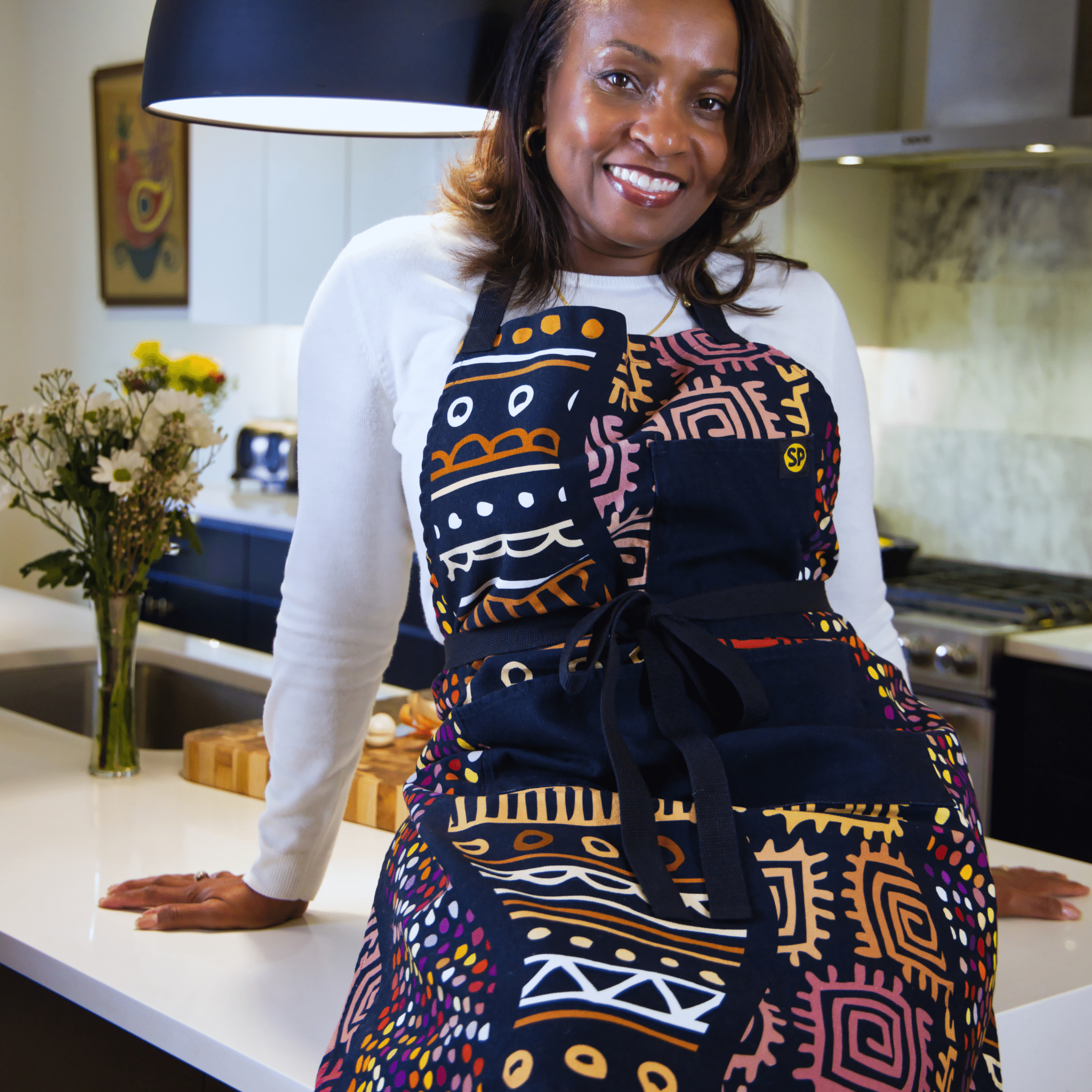 Woman wearing the Daddy Bob Apron by soulPhoodie featuring bold African-inspired patterns and deep black pockets.