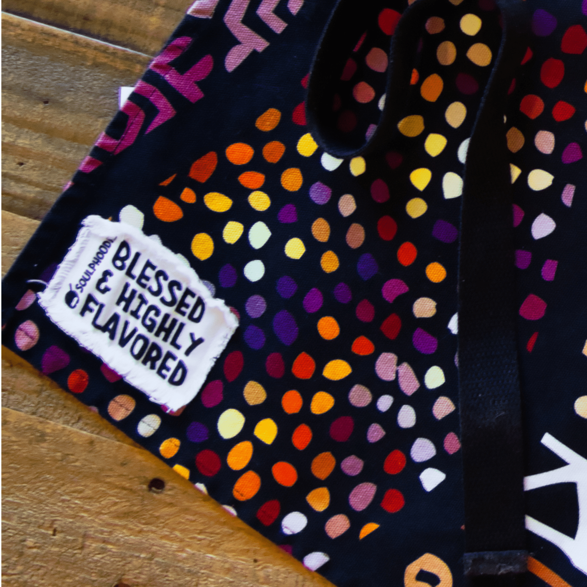 Close-up of the Daddy Bob Apron by soulPhoodie with its Blessed & Highly Flavored tag and bold multicolor pattern.