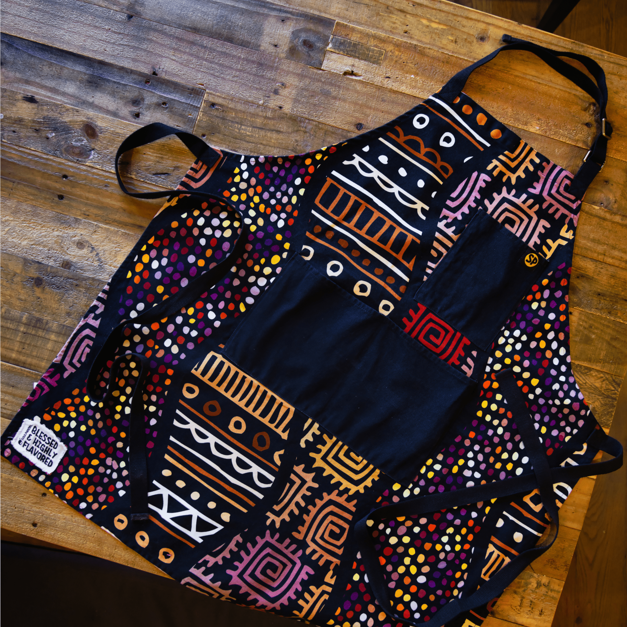 Flat lay of the Daddy Bob Apron by soulPhoodie featuring bold African-inspired patterns and deep black pockets.