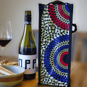 Colorful soulPhoodie wine bag with blue, red, and yellow circular design beside a bottle of wine on a wooden table.